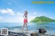 A woman standing on a rock in the ocean.