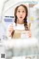 A woman holding a jar of water in front of a mirror.