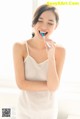 A woman brushing her teeth in front of a window.