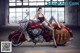 A woman sitting on a red motorcycle in a garage.