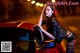 A woman leaning on the hood of a red car.