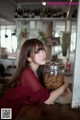 A woman sitting at a table with a jar of cookies.