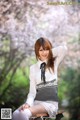 A woman sitting on a bench in front of a tree.