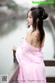 A woman in a pink dress sitting on a wooden bridge.