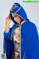 A man in a blue and gold costume with a hood.