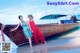 A couple of women standing next to a boat on a beach.