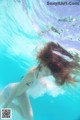 A woman in a white dress is underwater in the water.