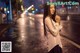 A woman standing in the middle of a city street at night.