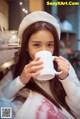 A woman sitting at a table with a cup of coffee.