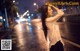 A woman standing in the middle of a city street at night.