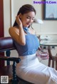 A woman sitting in a chair holding a glass of water.