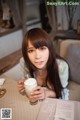 A woman sitting at a table with a cup of coffee.