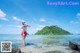 A woman standing on a rock in the ocean.