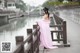 A woman in a pink dress standing on a bridge.