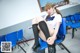 A woman sitting on a blue chair in a classroom.