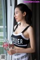 A woman in a black and white sports bra holding a bottle of water.