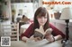 A woman sitting at a table reading a book.