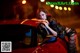 A woman leaning on the hood of a red car.