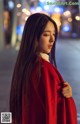 A woman in a red coat is standing on the street.