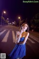 A woman in a blue dress standing in the middle of a street.