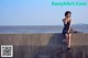 A woman sitting on a concrete wall talking on a cell phone.