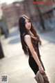 A woman in a black dress is walking down the street.