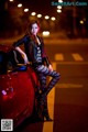 A woman sitting on the hood of a red car.