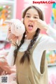 A woman holding a stuffed pig in front of her face.