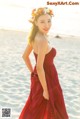 A woman in a red dress standing on a beach.