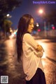 A woman standing in the middle of a street at night.