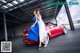 A couple of women standing next to a red sports car.