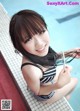 A woman in a black and white striped bathing suit sitting by a pool.