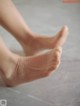 A close up of a person's bare feet on a tiled floor.