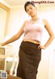 A woman in a pink top and brown skirt posing for a picture.