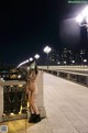 A naked woman wearing a face mask standing on a bridge.