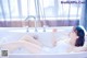 A woman laying in a bathtub brushing her teeth.