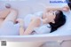 A woman laying in a bathtub with her legs crossed.