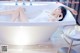 A woman laying in a bathtub with her legs up.