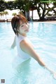 A woman in a white tank top standing in a pool.