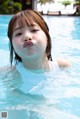 A young girl in a swimming pool making a funny face.