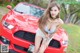 A woman sitting on the hood of a red car.