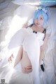 A woman with blue hair is laying on a bed.