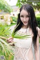 A woman in a white dress holding a palm tree.