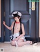 A woman in a maid outfit sitting on the floor.