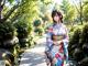 A woman in a kimono standing in front of a stream.