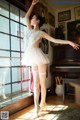 A woman in a white dress and stockings standing in front of a piano.