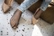 A close up of a woman's feet wearing a pair of nude colored shoes.