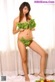 A woman in a bikini holding a bunch of vegetables.