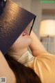 A woman laying on a bed with a book on her head.