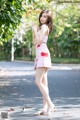 A woman in a pink dress standing on a road.